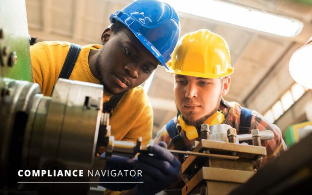 Two people in hard hats examining machinery