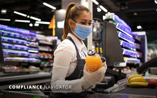 Grocery store attendance in a face mask and gloves scanning a customers groceries