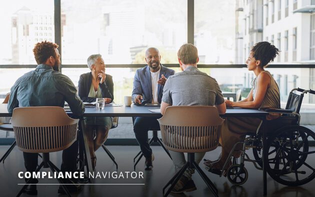 Group sitting at a conference table. Four are in chairs and one is in a wheelchair