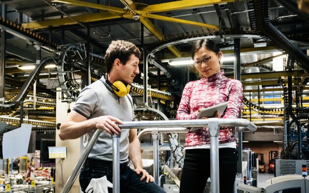 Man and woman in a manufacturing plant looking at tablet