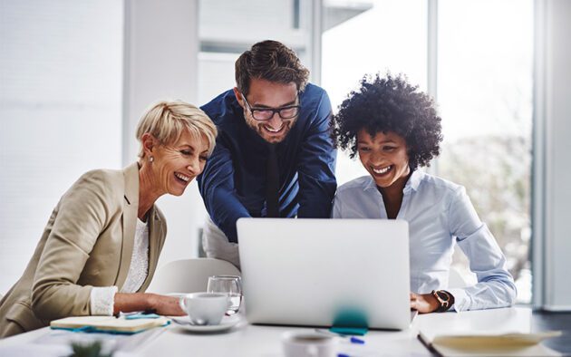 3 people around a laptop smiling and laughing