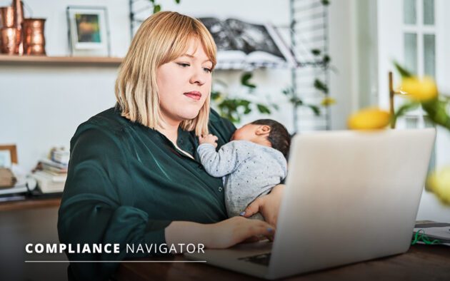 A person works on a laptop while holding a sleeping baby, surrounded by home decorations and yellow flowers in the foreground.