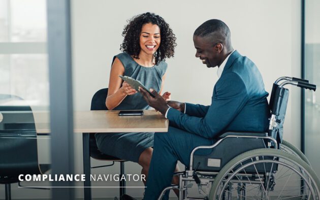Man in wheelchair and woman sitting at table filling out a clipboard