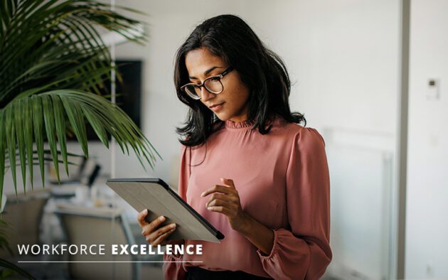 A woman in a pink blouse and glasses uses a tablet in an office setting. Text on the image reads "Workforce Excellence.